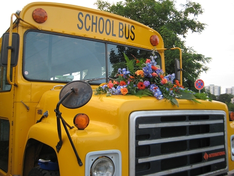 Schulbus mit Blumenbouquet auf Kühlerhaube für Hochzeiten