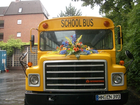 Schulbus mit Blumenbouquet auf Kühlerhaube für Hochzeiten